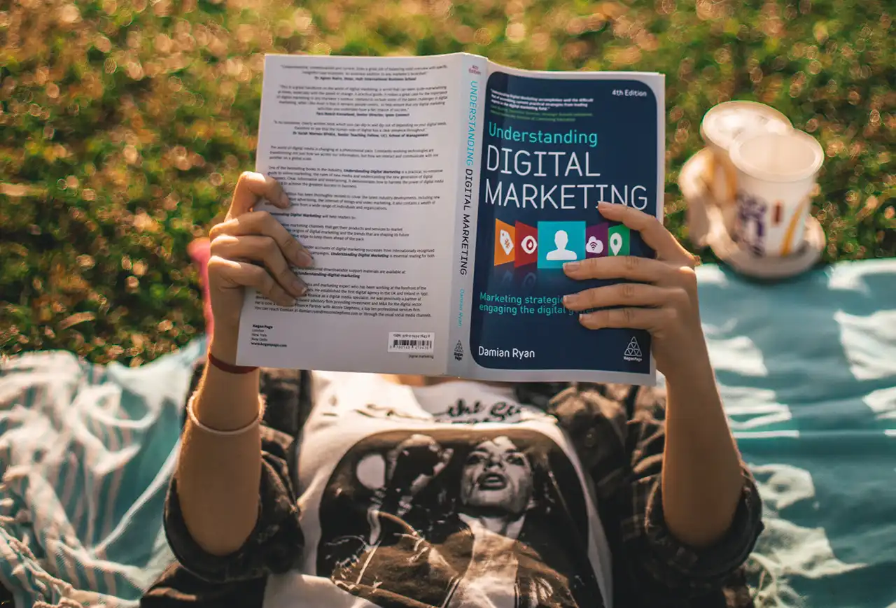 Person reads digital marketing book outdoors.