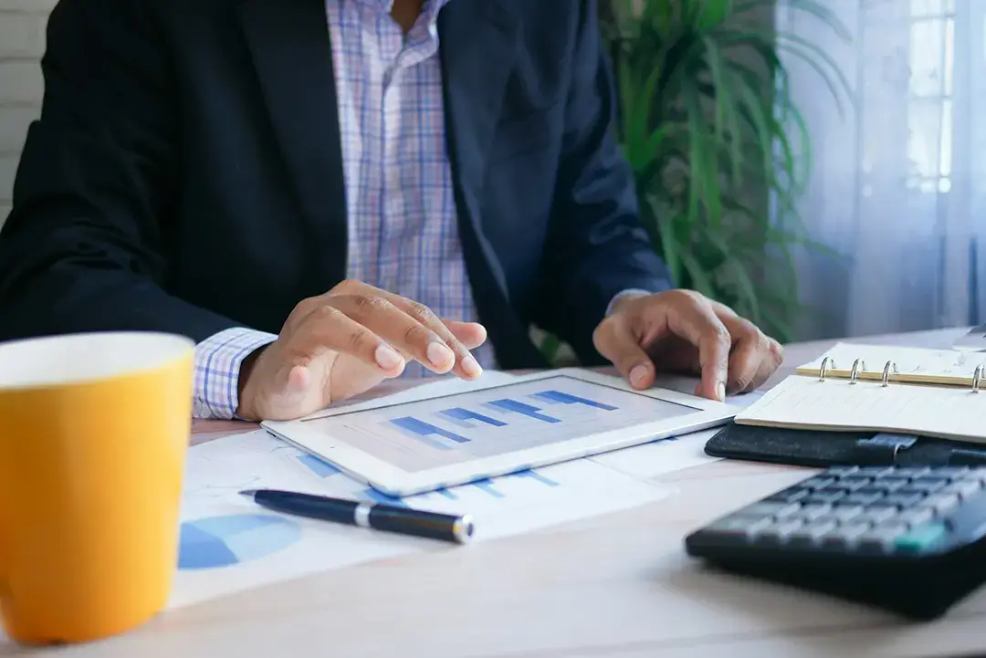 Businessman analysing tablet data at desk.