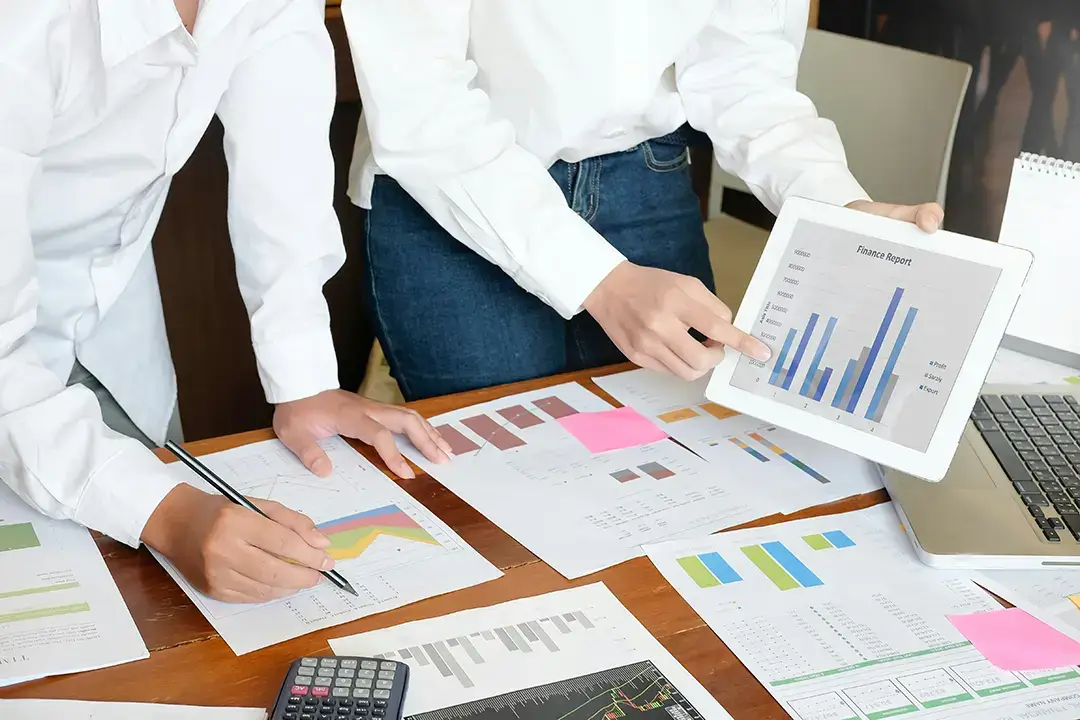 Team analysing financial charts and graphs on tablet.