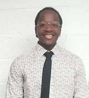 Smiling man wearing glasses and a patterned shirt.
