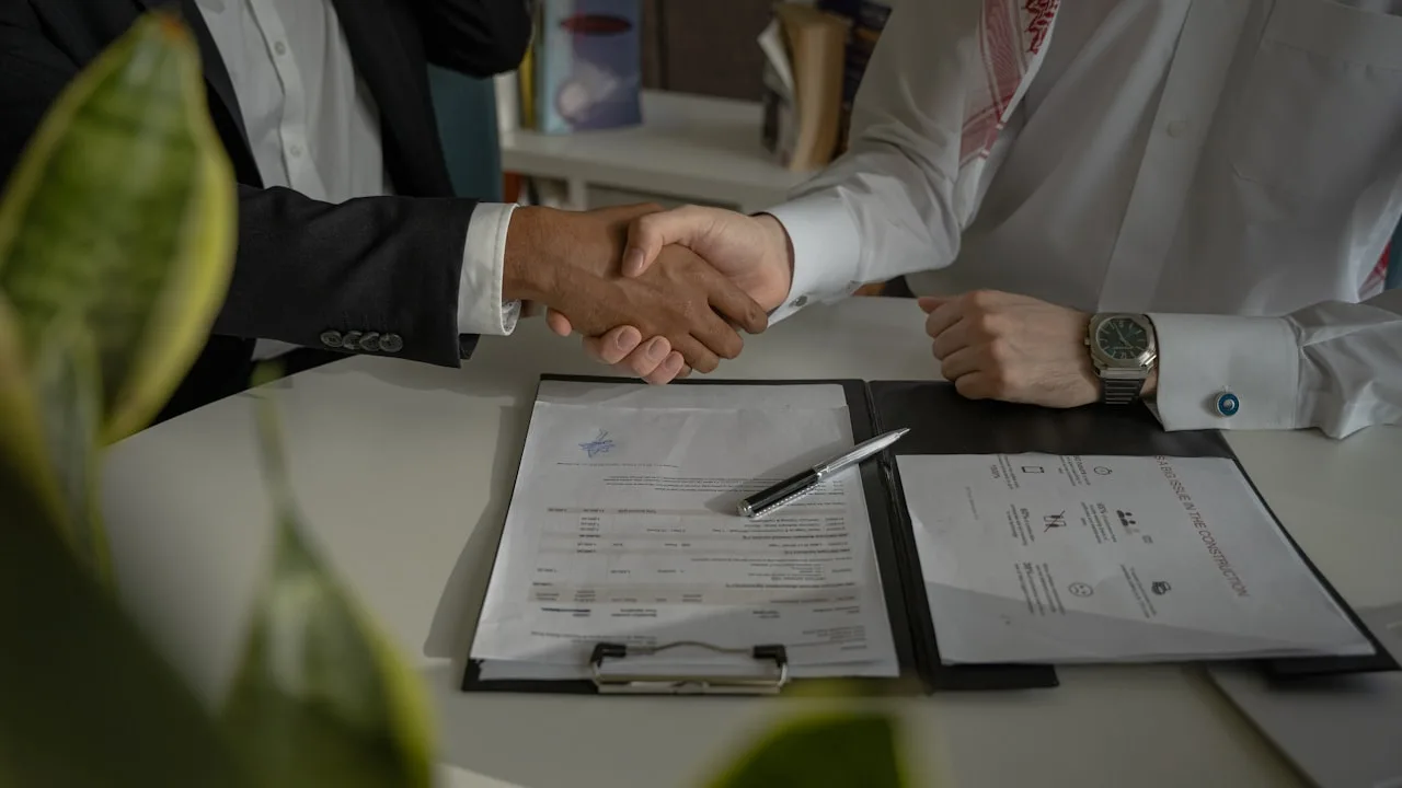 Two people shaking hands over documents