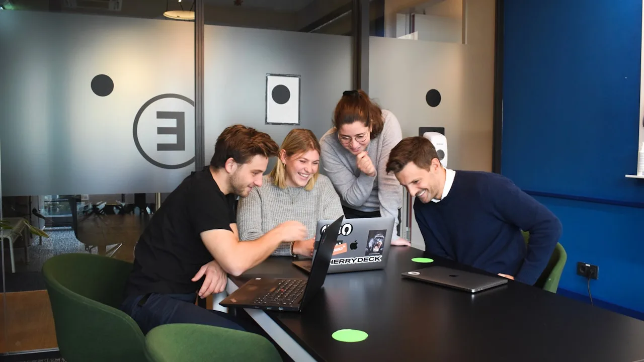 Group of people smiling around laptops