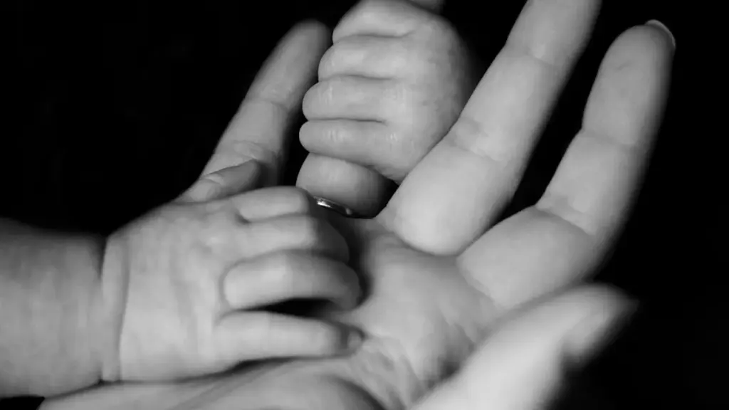 Baby hands holding adult finger in black and white