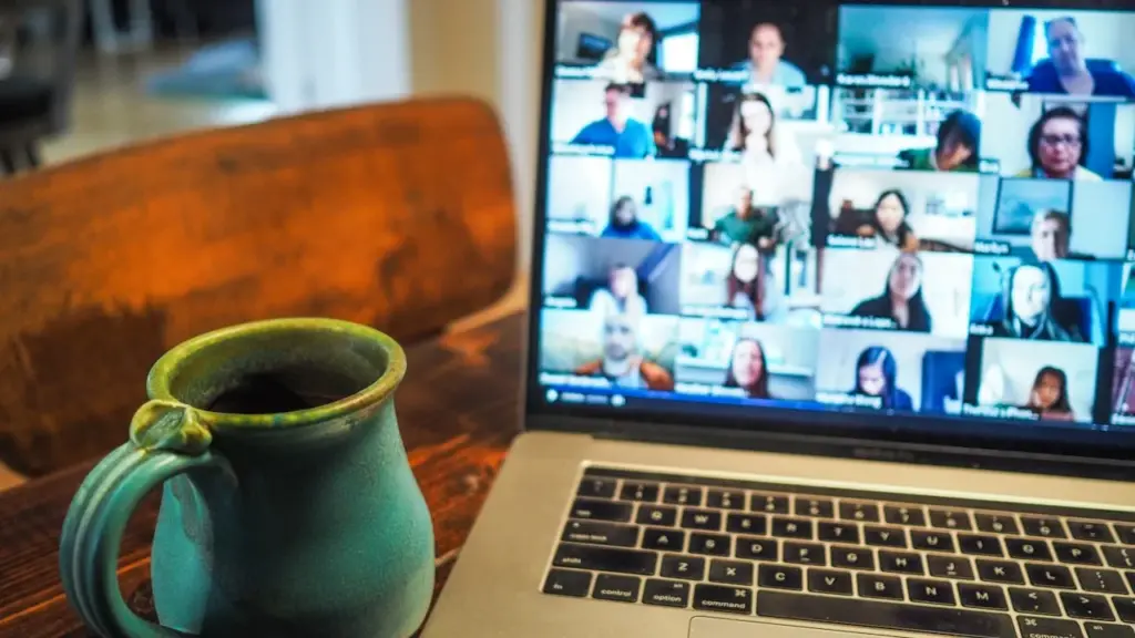 Green mug beside laptop showing video call