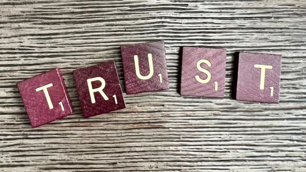 Scrabble tiles spelling TRUST on wooden surface